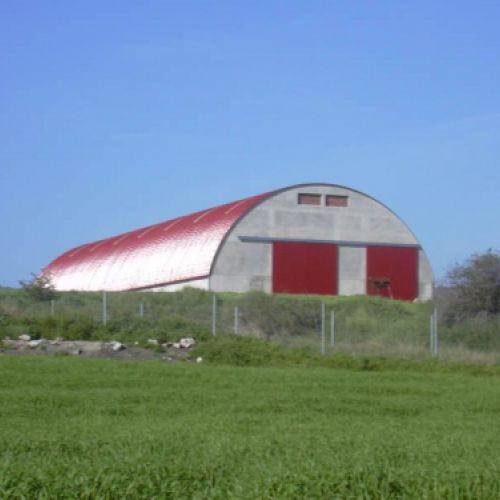 Nave agrícola con techo curvado en el campo
